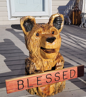Chainsaw Carving Bear holding a sign.